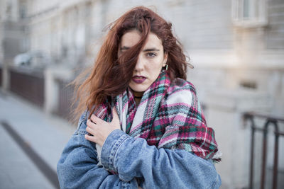 Portrait of woman standing on footpath in city