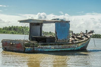 Abandoned boat moored on sea against sky