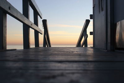 Surface level of pier over sea against sky during sunset