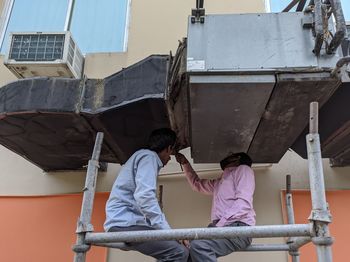 Two workers inspecting outdoor air conditioner ventilation system