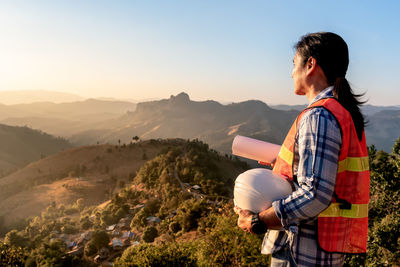 Side view of man standing on landscape against mountain range