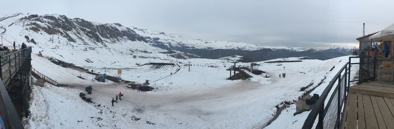 Panoramic view of snow covered landscape in front of mountains against sky