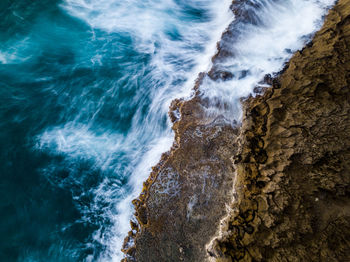 Aerial view of rocky cliff by sea