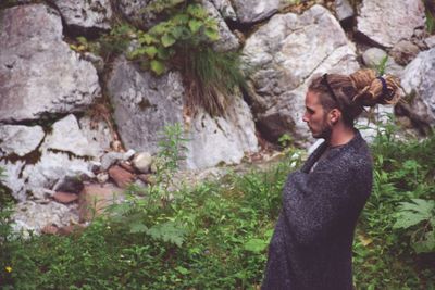 Side view of thoughtful man wrapped in blanket standing outdoors