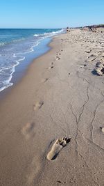 Footprints on sand at beach against sky