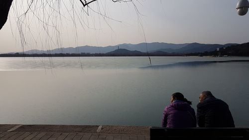 Rear view of people looking at lake against sky