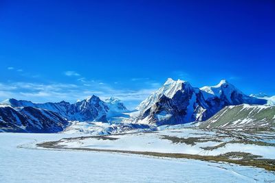 Scenic view of snow mountains against blue sky