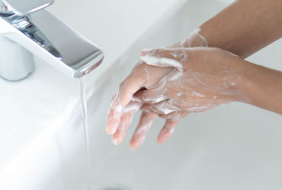 Close-up of hand touching water in bathroom