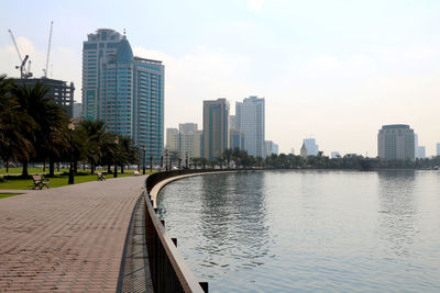 Modern buildings by river against sky in city