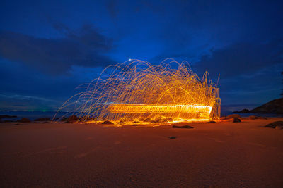 Firework display on beach against sky at night