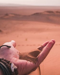 Close-up of hand on sand at beach