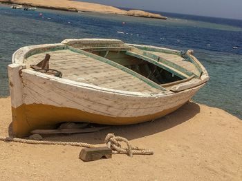 Boat moored on beach against sky