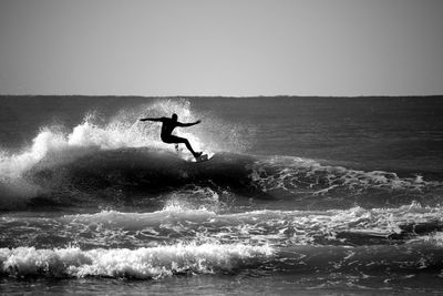 Silhouette of woman surfing in sea