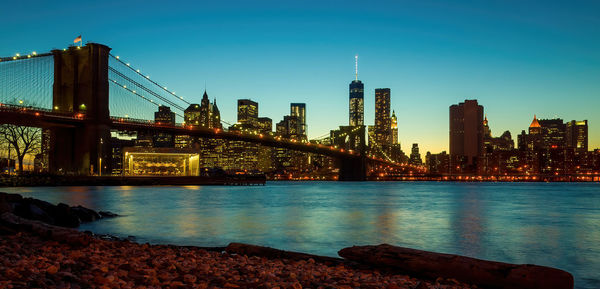 Illuminated bridge over river against sky at night