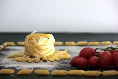 Close-up of uncooked pasta with tomatoes on table