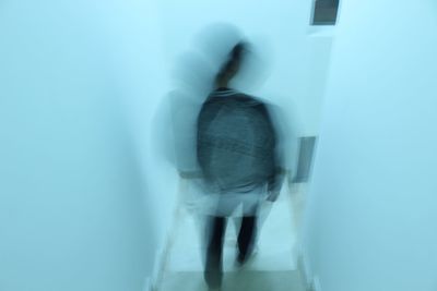 Rear view of woman standing against wall