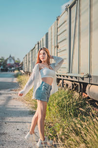 Full length portrait of young woman against sky