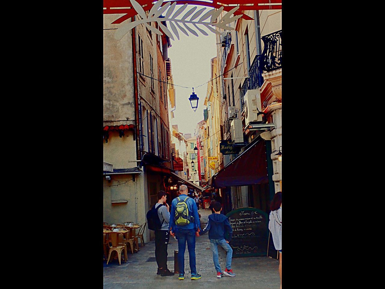 REAR VIEW OF PEOPLE WALKING BY BUILDINGS