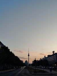 View of berlin tv tower and street against clear sky during sunset