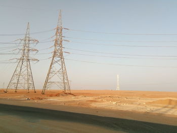 Electricity pylon on field against clear sky