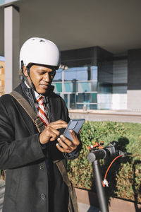 Executive man trying to unlock an electric scooter with the application on the mobile phone to move 