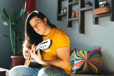 Side view, man with long hair playing acoustic guitar relaxed attitude