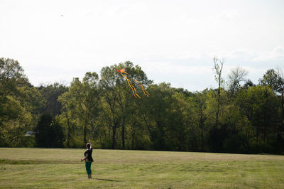 Man standing on field by trees against sky