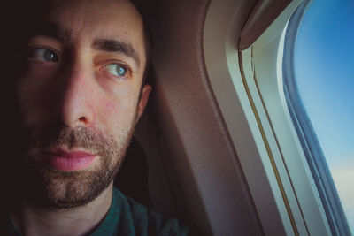 Thoughtful man looking through window in airplane