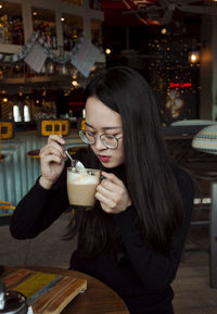 Young woman drinking glass at restaurant