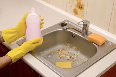 High angle view of man with bottle cleaning sink at home