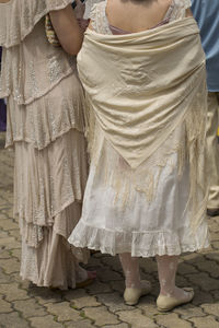 Low section of women standing in traditional clothing on footpath during celebration