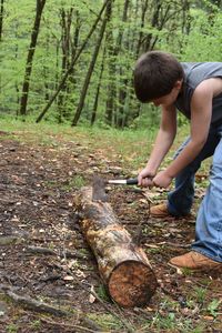 Full length side view of my son chopping a log