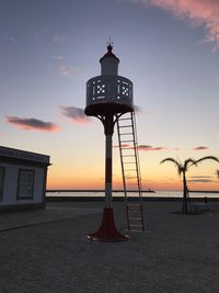 Silhouette tower on beach against sky during sunset