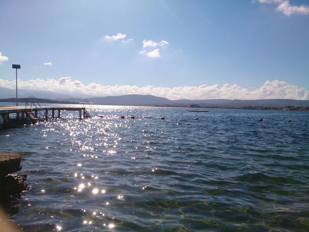 water, sea, sky, waterfront, scenics, tranquil scene, tranquility, rippled, beauty in nature, blue, cloud - sky, nature, idyllic, cloud, mountain, day, outdoors, sunlight, remote, non-urban scene