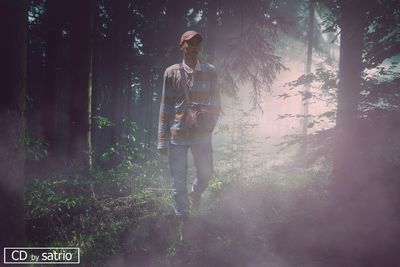 Man standing by trees in forest