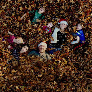 Portrait of happy family lying down on dry leaves during autumn