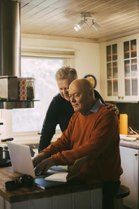 Homosexual couple using laptop in kitchen at home