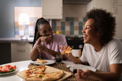 Mixed race woman laughing at joke near friend