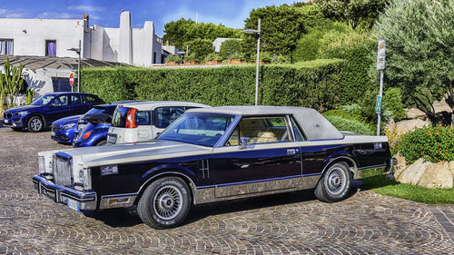 Vintage car on road by buildings against sky