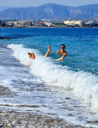 People enjoying in sea against mountain