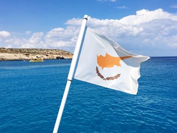 Flag on boat in sea against blue sky