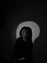 Portrait of young woman standing against wall
