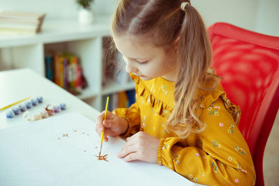 Girl painting on paper at home