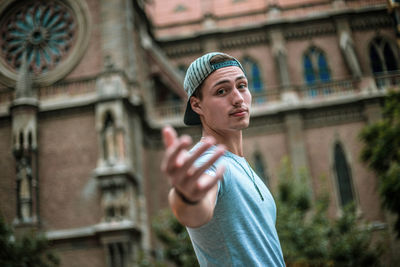 Portrait of man gesturing while standing against building