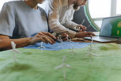 Colleagues with wind power model and laptop in office