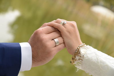 Cropped image of bride and groom wearing rings against tree