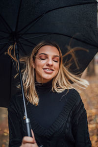 Close-up of young woman holding umbrella during rain