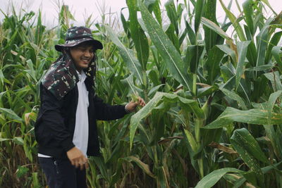 Smiling man standing by plants in farm