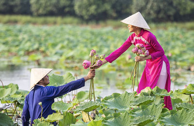 Side view of man giving flowers to woman in lake