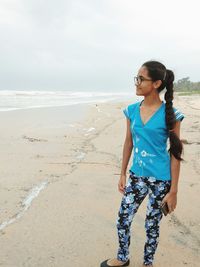 Girl standing at beach against sky